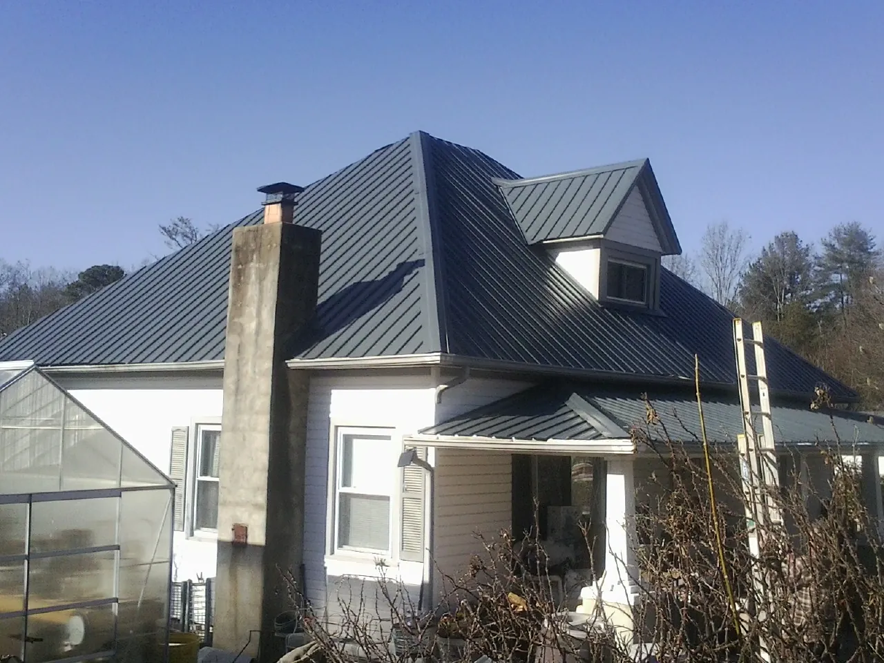 Dark blue standing seam metal roof on a white farmhouse with dormer — Slate & Tile Roof Repair by Roofing Brothers in Craigsville
