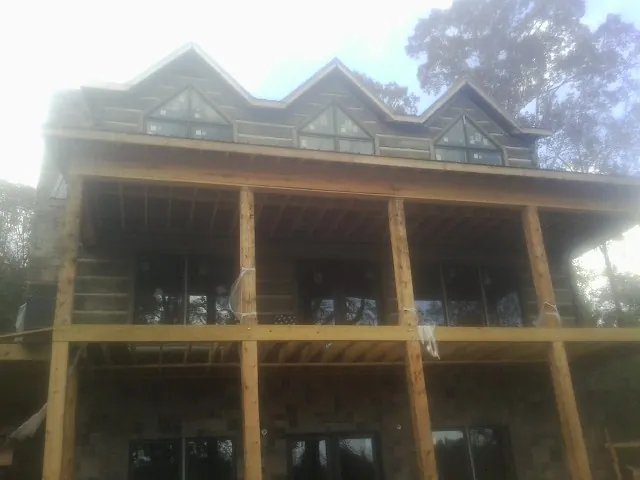Dormers and porch framing on a large log home under construction — Roof Coating work by our crew in Craigsville