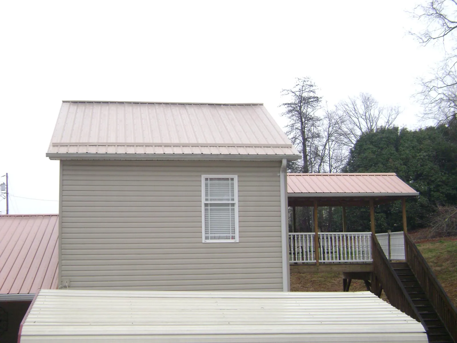 Tan metal roofs on a two story addition and attached porch, from a Roof Replacement job in Craigsville