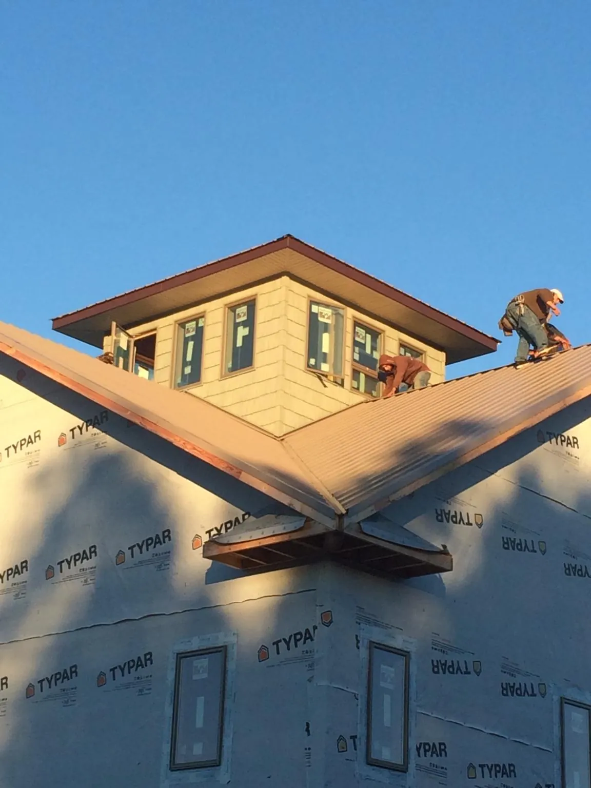 Roofers working around a rooftop cupola on a new metal roof at sunset — Roof Waterproofing in Craigsville by Roofing Brothers